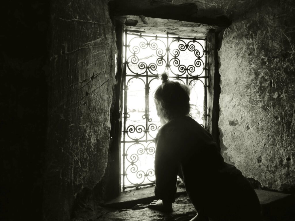 Girl looking outside of traditional Moroccan window in Ait Bougmez valley